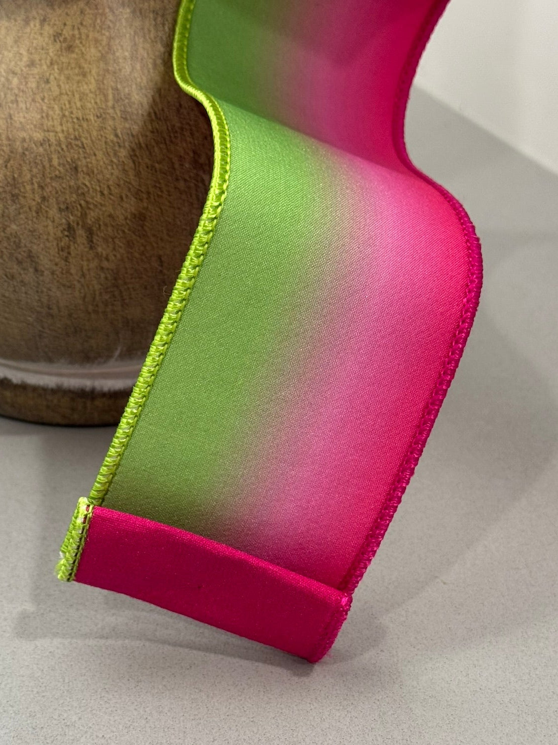 Gradient ribbon transitioning from green to pink on a neutral background